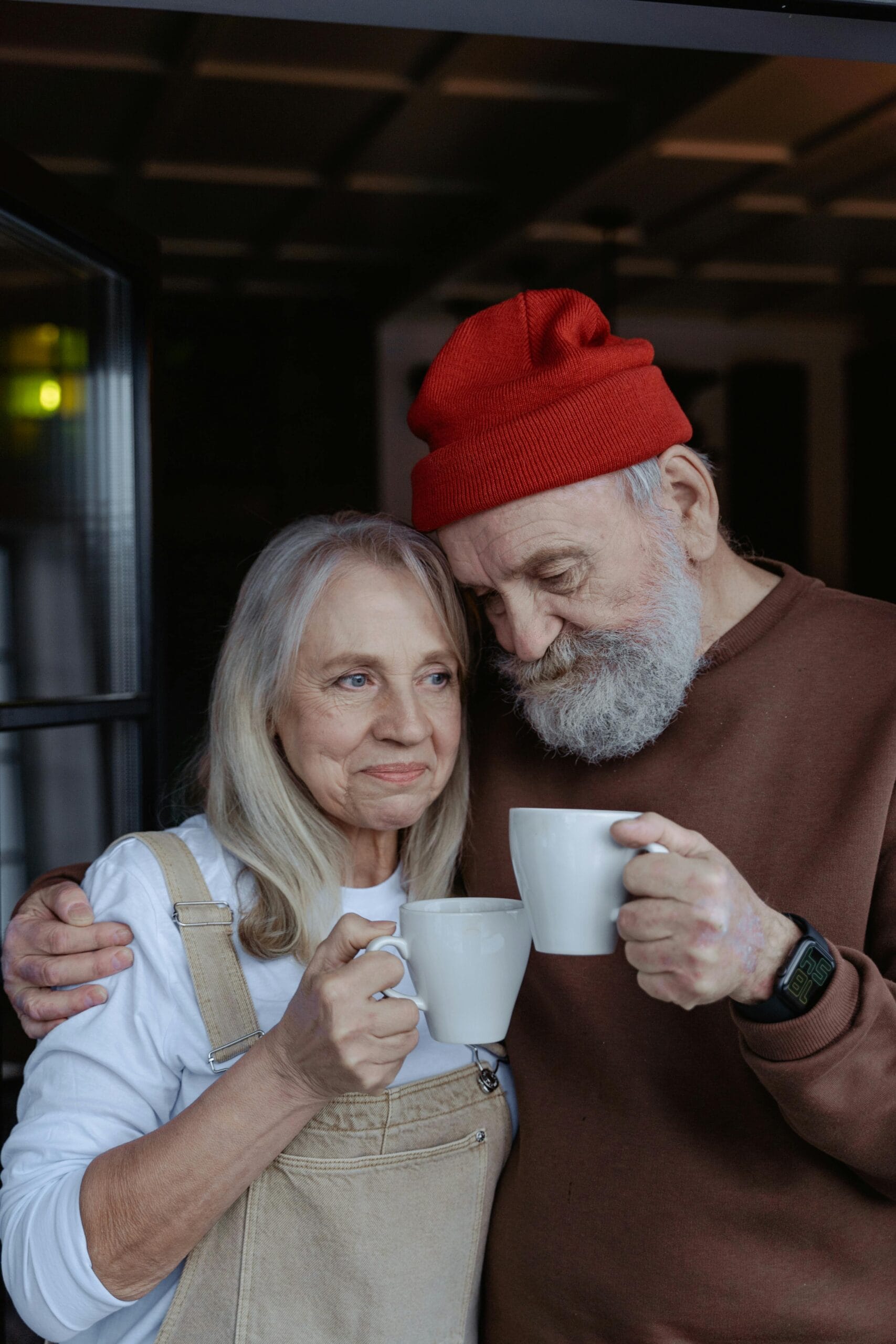 Senior couple sharing a warm moment with coffee indoors.